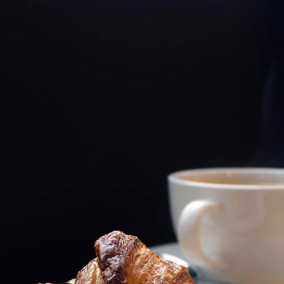 A house-made croissant with a cup of coffee